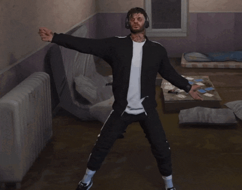 a man with a tattoo on his face is dancing in a room with cards on the floor