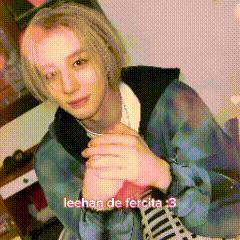a young man in a blue jacket is sitting in a room holding a pink heart .