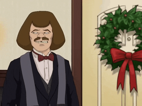 a man in a suit and bow tie is standing in front of a wreath