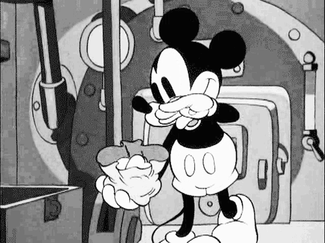 a black and white cartoon of mickey mouse eating a donut in a room .