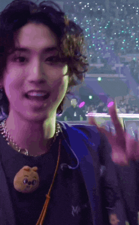 a young man with curly hair is giving the peace sign