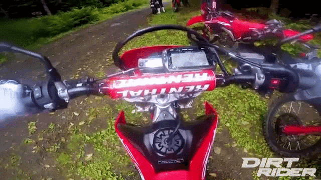 a dirt bike with a renthal handlebar is parked on a dirt road