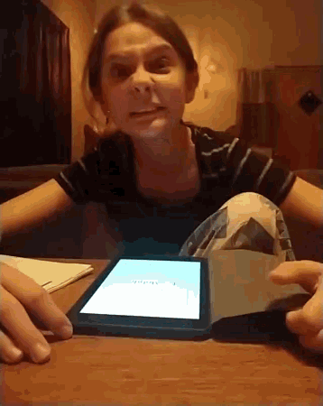 a young girl sits at a table with a tablet and a book opened to a page that says ' journal ' on it
