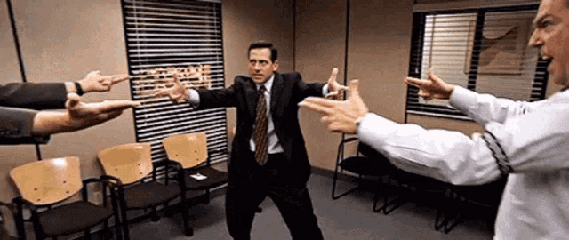 a man in a suit and tie is surrounded by people pointing at him .