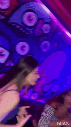 a woman is dancing in front of a purple wall with a drawing on it