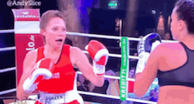 two women are boxing in a ring and one of them is wearing a red and white top .
