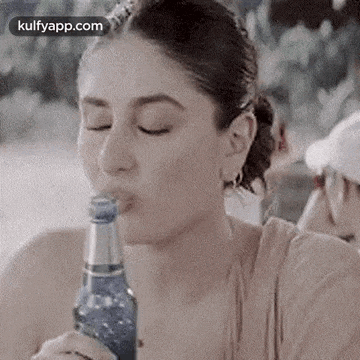 a woman is drinking water from a bottle .