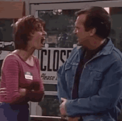 a man and a woman are standing next to each other and talking in front of a store door .