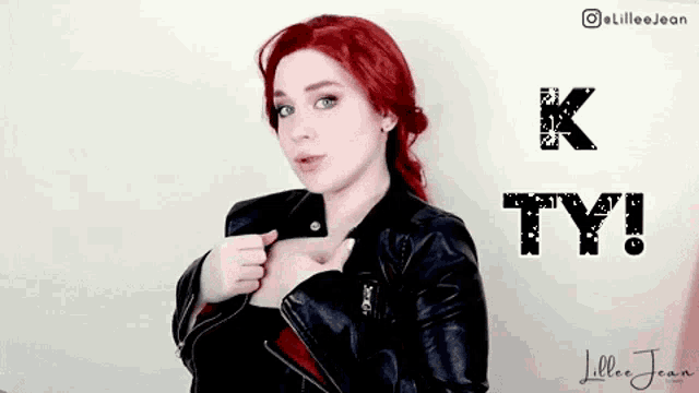 a woman with red hair is wearing a black leather jacket .