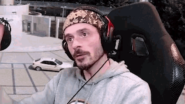 a man with a beard is wearing headphones and a headband while sitting in a chair .