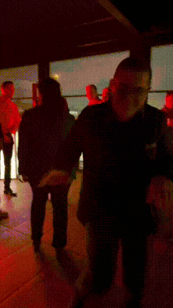 a group of people standing in a dark room with red lights behind them