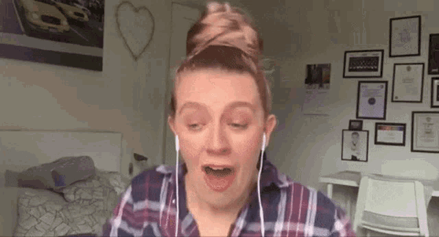 a woman wearing headphones and a plaid shirt is making a funny face