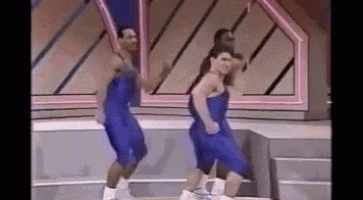 two men are dancing on a stage wearing blue shorts and boxing gloves .