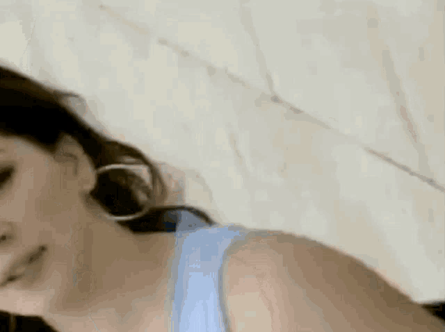 a woman wearing a blue tank top and hoop earrings is laying down .