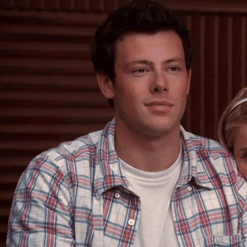 a man in a plaid shirt is sitting next to a little girl