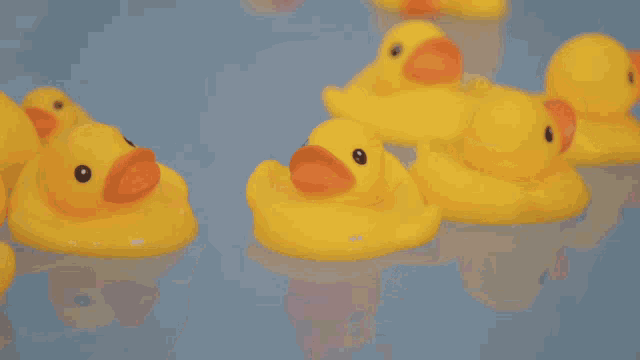 a person is holding a yellow rubber duck in their hand in a bathtub