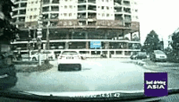 a car is driving down a street in front of a building with a sign that says just driving asia