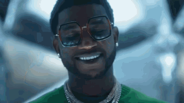 a man wearing glasses and a green shirt smiles for the camera
