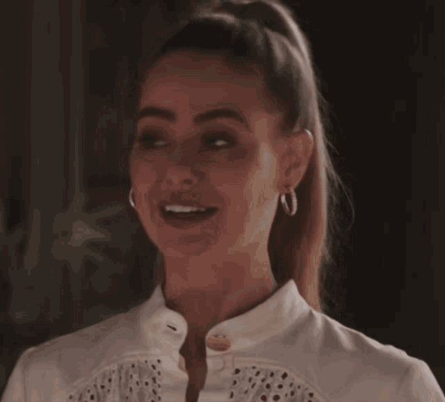 a close up of a woman 's face with a ponytail and earrings