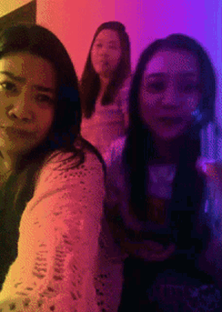 three women are posing for a picture in front of a purple and orange background