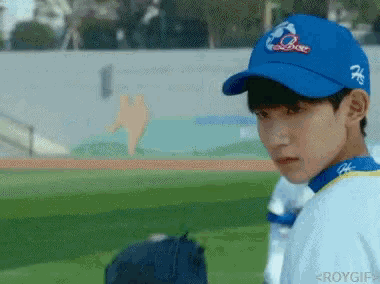 a baseball player wearing a blue hat with the letter q on it stands on a field
