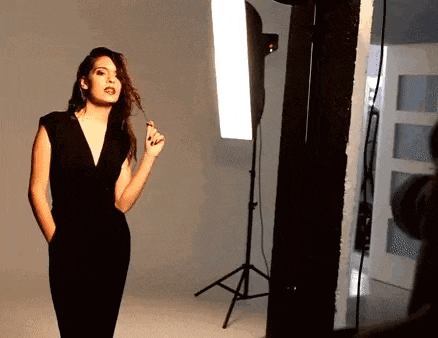 a woman in a black dress is being photographed in a studio .