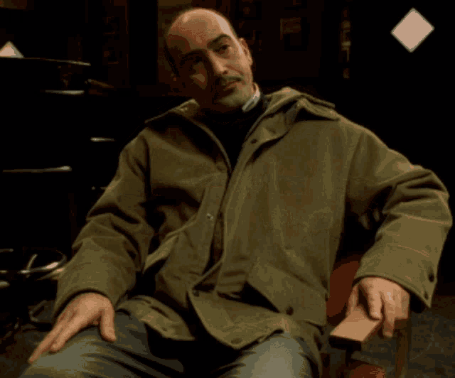 a man wearing a green jacket is sitting in a chair