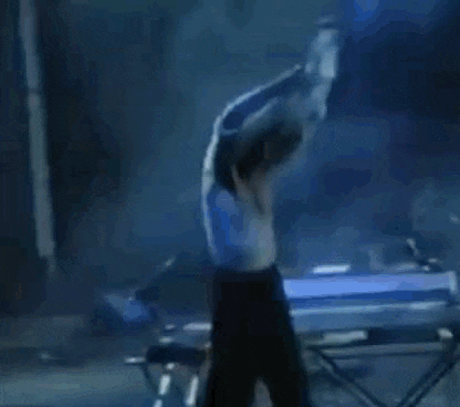 a shirtless woman is dancing on a stage in a dark room .
