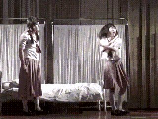 two girls standing next to each other in front of a bed