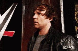 a man in a black leather jacket is standing in front of a sign that says live .