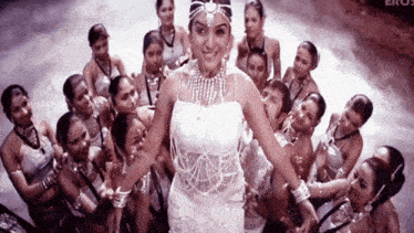 a woman in a white dress is surrounded by a crowd of women