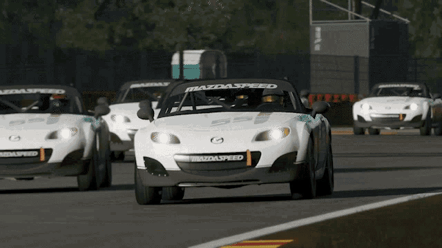a row of white mazdaspeed cars are driving down a track