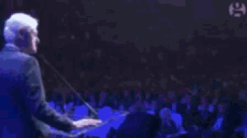 a blurry picture of a man in a suit standing in front of microphones