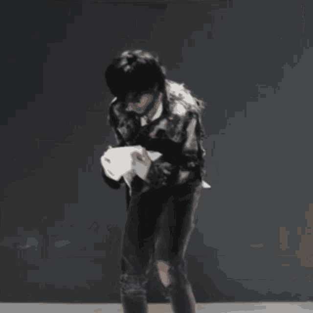a man in a black jacket is holding a piece of paper in his hand .
