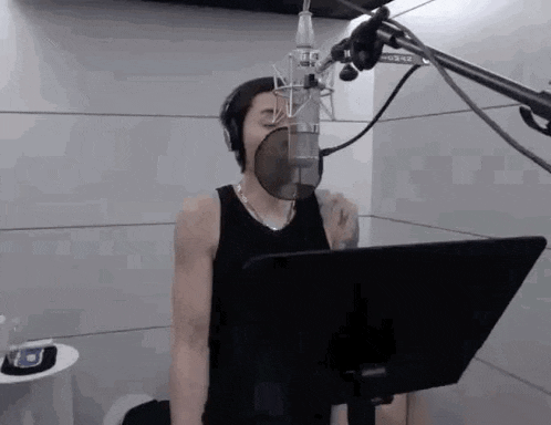 a man is singing into a microphone in a recording studio while wearing headphones .