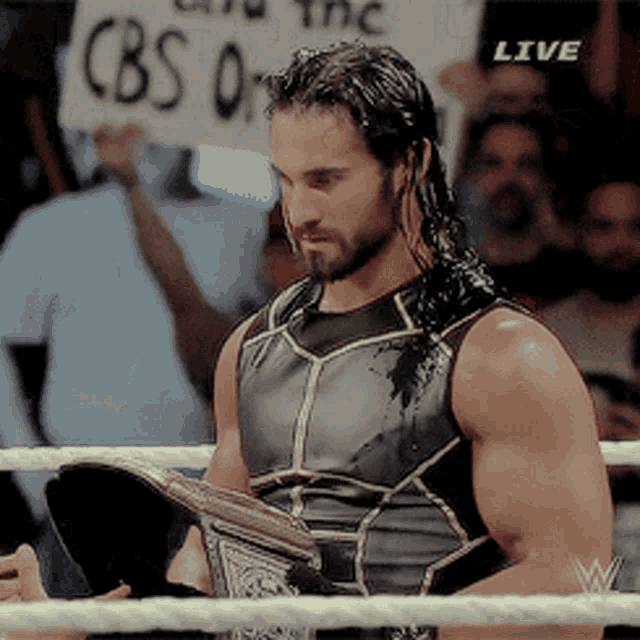 a man in a wrestling ring is holding a cbs 0 sign
