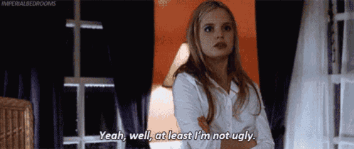 a woman is standing in a room with her arms crossed and saying yeah well at least i 'm not ugly