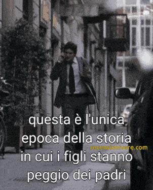 a man in a suit and tie is talking on a cell phone on a street
