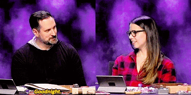 a man and a woman are sitting at a table with a sign that says `` goodnight '' .