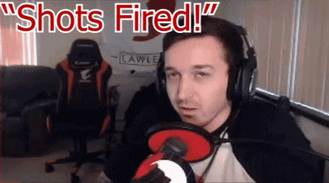 a man wearing headphones stands in front of a microphone with the words " shots fired " written above him