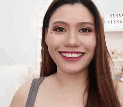 a woman with braces on her teeth is smiling while wearing a gray tank top .