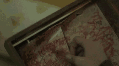 a person is holding a piece of paper with blood on it in a picture frame .