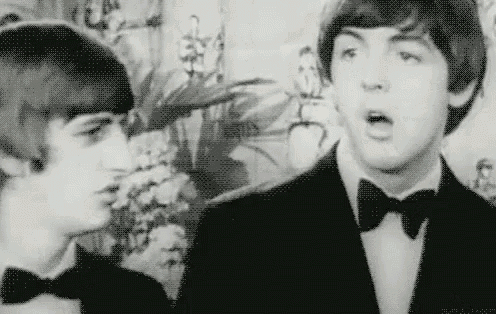 a black and white photo of two young men in tuxedos talking to each other .