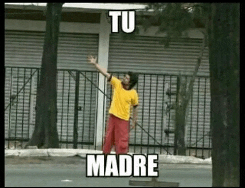 a man in a yellow shirt and red shorts is standing in front of a fence with his arm outstretched .