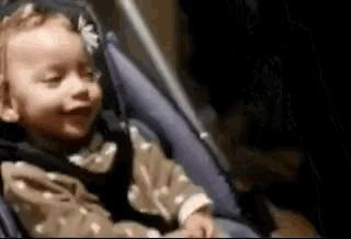 a baby is sitting in a car seat smiling .