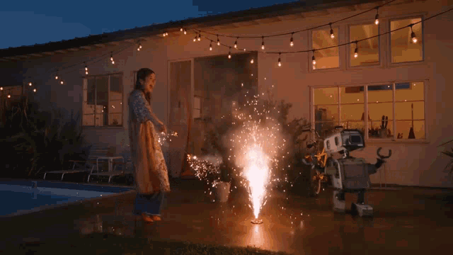 a woman standing next to a robot holding sparklers