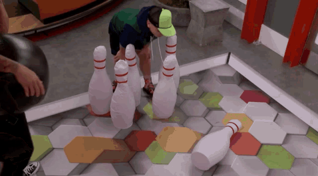 a man in a green shirt and a green hat is playing bowling