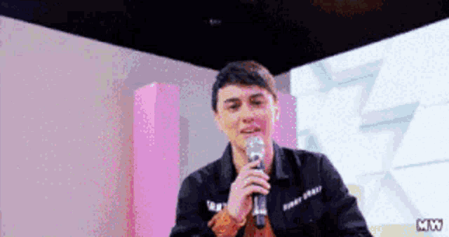 a man in a black jacket is holding a microphone in his hand .