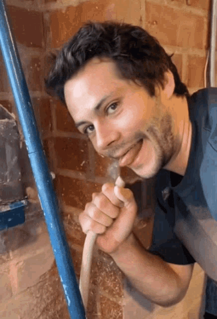 a man is drinking water from a hose with his tongue hanging out