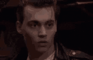 a man is making a surprised face while wearing a leather jacket .